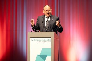 Oberbürgermeister Christian Specht, eine älterer Mann mit Halbglatze. Er trägt eine Brille und hat einen braunen Anzug mit Schlips an. Er steht am Rednerpult und hält einen Vortrag.