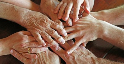 Die Hände von Personen verschiedenen Alters berühren sich