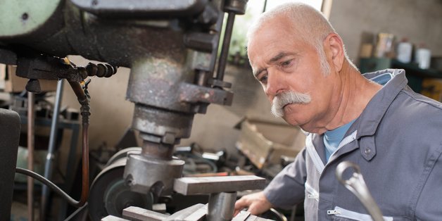 Älterer Herr arbeitet in Maschinenbauwerkstatt