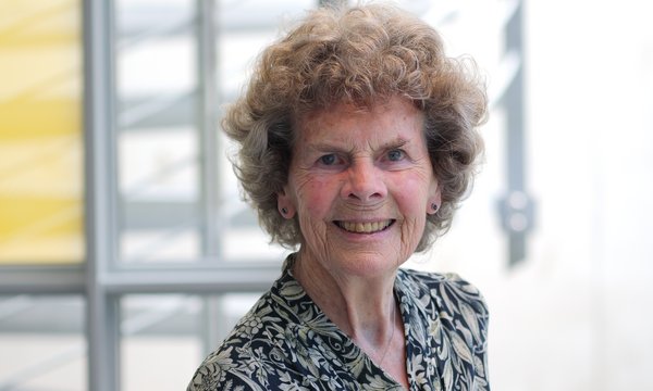 Dr. Heidrun Mollenkopf: Alte Frau mit kurzen braunen, gelockten Haaren. Sie trägt ein schwarz-weiß gemusterte Bluse.