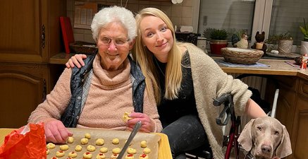 Das Leben ist bunt und schmeckt gut! Seniorin mit Enkelin und Hund am Küchentisch, mit Teigschüssel, Backbleck, Plätzchenrohlingen und Rollator