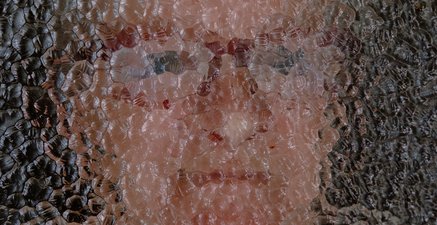 Close up von dem Gesicht einer älteren Frau hinter einer Milchglasscheibe