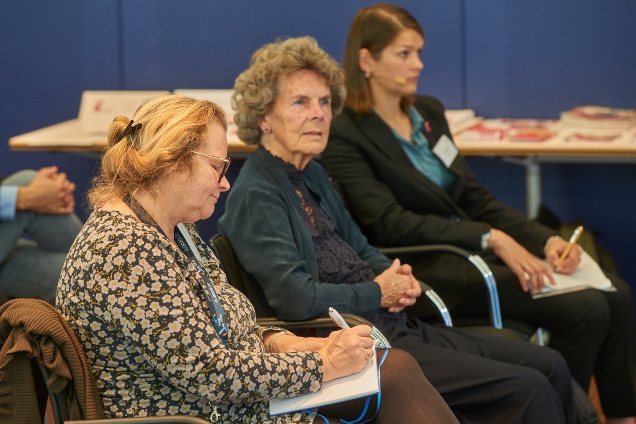 Drei Frauen aus dem Publikum verfolgen einen Redebeitrag