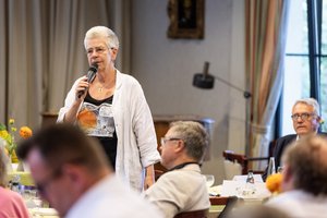 Ein ältere Frau aus der Zuhörerschaft spricht in ein Mikrofon.