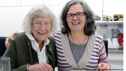 Ein alte Frau sitzt mit einer Frau mittleren Alters an einem Küchentisch