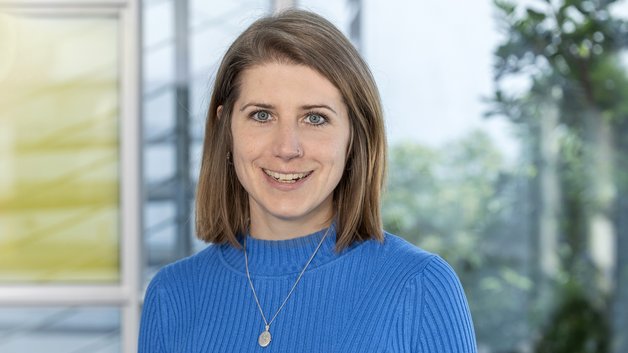Portrait Johanna te Kronnie: Junge Frau mit schulterlangem brauen Haar. Sie trägt eine blauen Pullover.