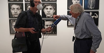 Vor einer Wand mit Portraits wird der Fotograf Walter Schels vom Deutschlandfunk interviewt