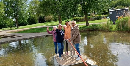 Fünf Frauen auf einem Floß auf dem man sich durch ziehen an einem Seil fortbewegen kann.