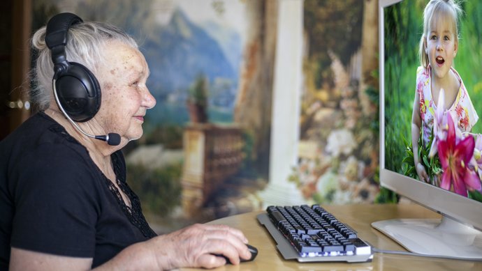 Ein alte Frau sitzt von einem Computer und skypt.