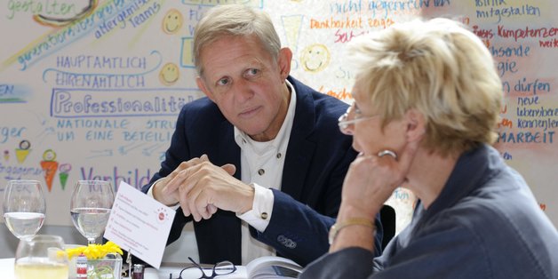 Mann und Frau an einem Arbeitsgruppen-Tisch sitzend in ein Gespräch vertieft.