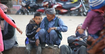 Ein Junge umarmt einen älteren Nepalesen und schaut dabei in die Kamera