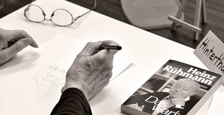 Ein Portrait von Hein Rühmann wird von einer Seniorin mittels Bleistift kopiert.