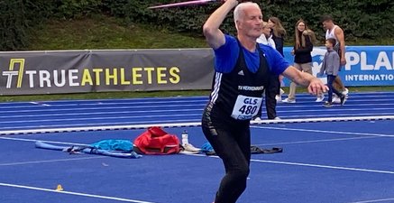 Ein schon etwas älterer Mann mit athletischer Figur im Sporttrikot mit einem Speer in der rechten Hand beim Anlauf