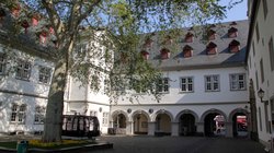 Blick von einem Innenhof auf ein historisches Gebäude mit einem Laubengang. Es ist das Koblenzer Rathaus.