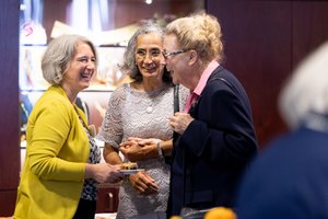 Ein junge Frau unterhält sich mit zwei älteren Frauen. Sie lachen miteinander.