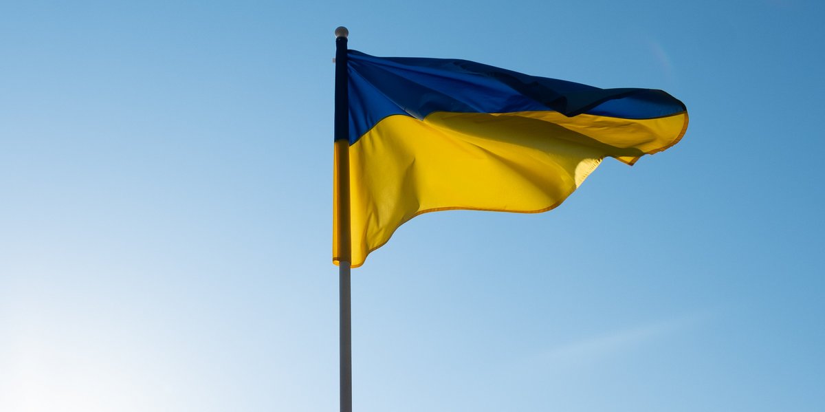 Eine Ukraine Fahne weht im Wind vor blauem Himmel.