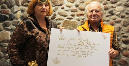 Grußkarte Rentnerehepaar hält selbstgemaltes Poster zum Hochzeitstag in die Kamera