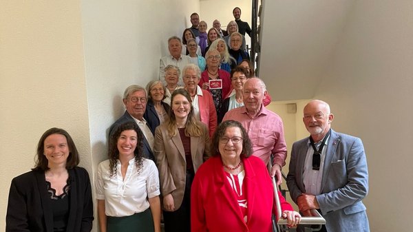 Eine Gruppe von Menschen steht auf einer Treppe und schaut Richtung Kamera.