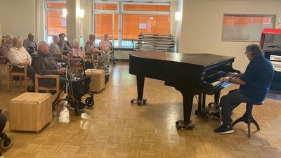 ©Bethanien gGmbH In einem Saal sitzen ältere Menschen und hören einem Klavierkonzert zu.