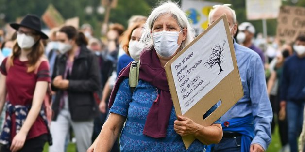 Ältere Frau auf einer Demonstration mit einem Pappschild in der Hand.